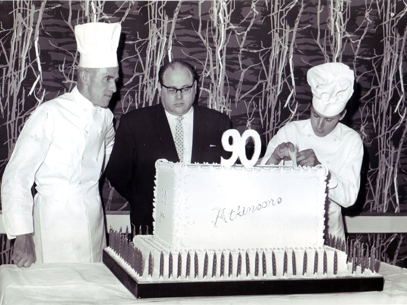 The restaurant manager at Atkinsons department store, Mr B Cohen, looks on as members of his staff put the finishing touches to this giant cake made for the firm's 90th birthday celebrations in May 1962. The baker-craftsmen are Mr D R Phipps (left) and Mr G R Scott