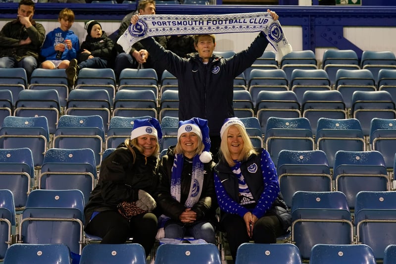 A group of Pompey fans with Blues-inspired Christmas hats on, and a fan proudly displaying his scarf. 