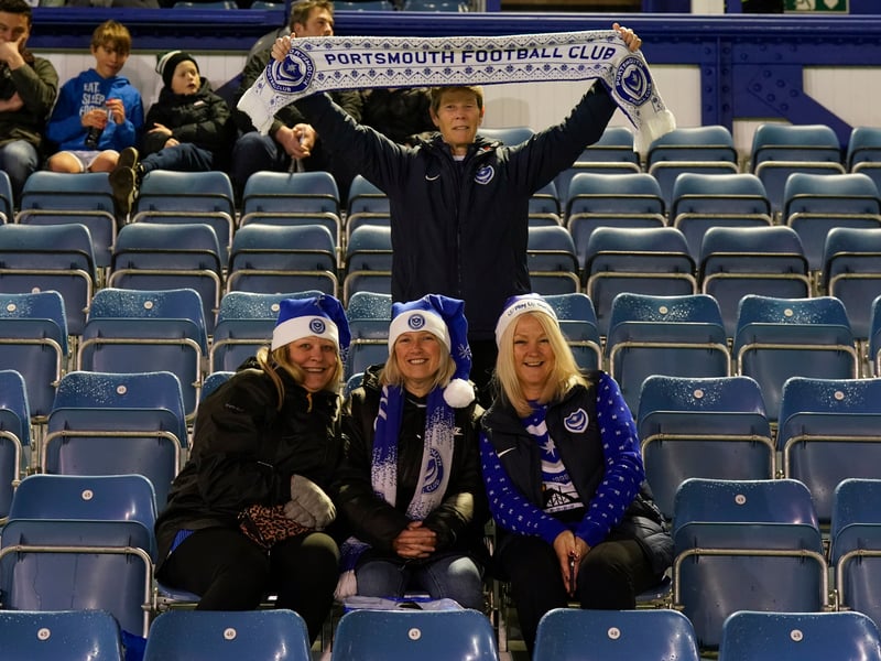 A group of Pompey fans with Blues-inspired Christmas hats on, and a fan proudly displaying his scarf. 
