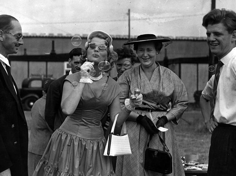 Miss Joan Regan, the singing star from the Queens Theatre, blowing bubbles after opening the Warton RAF station garden party. On the left is the Co, Group Captain H stones, and on the right Mrs. V.G.E. shaw, garden party secretary