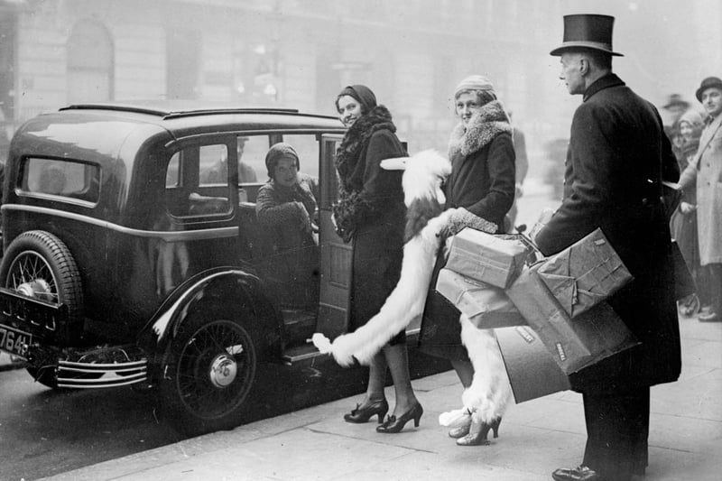 December 3 1930:  Women load their Christmas shopping into a car with the aid of an attendant from Whiteley's department store in London.  (Photo by Fox Photos/Getty Images)