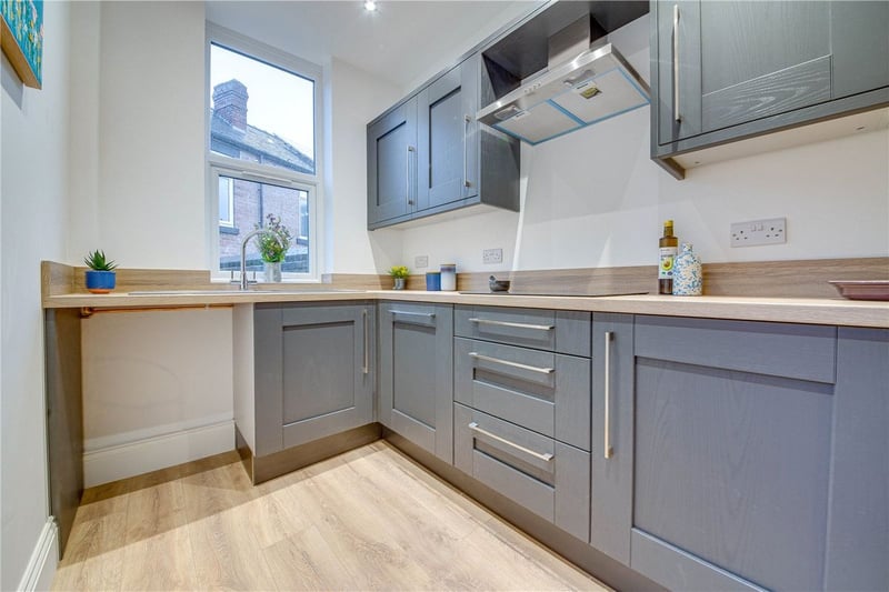 The newly-renovated kitchen has integrated appliances, storage space, a modern design, and window overlooking the rear garden.