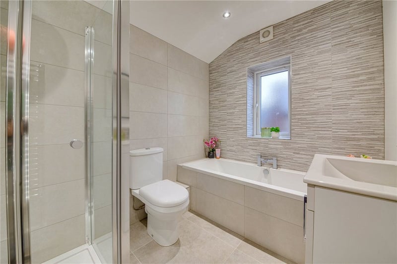 The bathroom has a sleek, modern design with recently replaced fittings. It includes a bath as well as a separate walk-in shower.