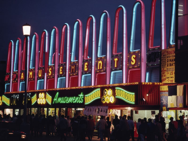 A night view of holiday makers walking along the Golden Mile, illuminated by neon signs in April 1987.  (Photo by RDImages/Epics/Getty Images)
