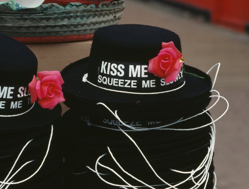 Novelty hats with the slogan kiss me quick, squeeze me slowly are stacked up in a shop