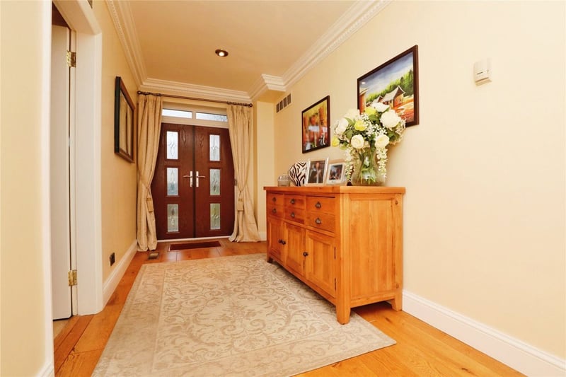 The entrance hallway features wooden flooring, furniture and double doors.