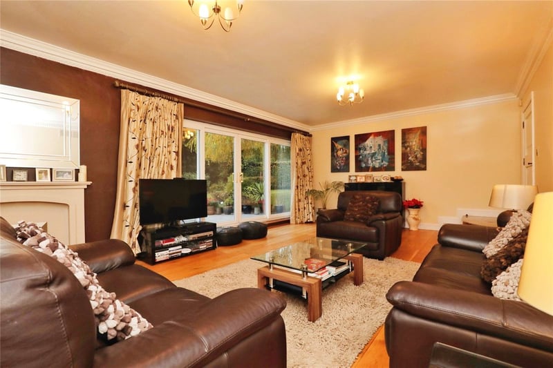 The lounge is set in a corner of the open-plan downstairs, featuring patio doors and cosy decor.