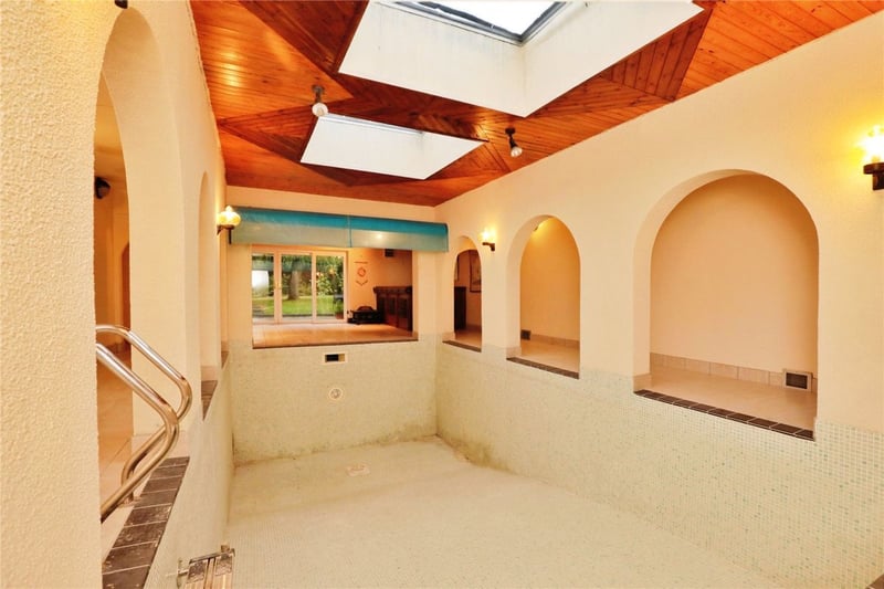 A heated, indoor swimming pool with skylight windows, arched walls, and changing rooms.