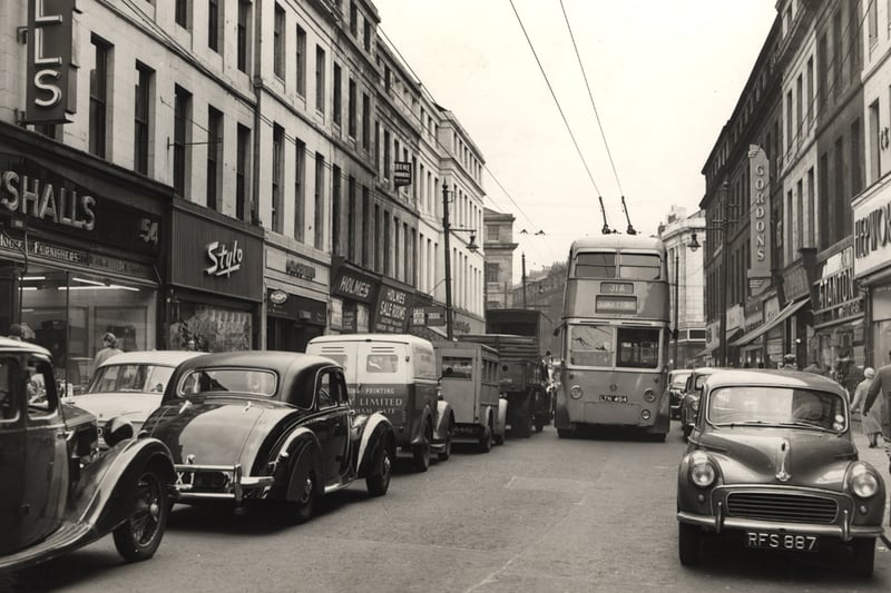 The photograph shows Clayton Street in the 1950's. The trolley bus in the centre of the picture is the number 31 to Grange Estate. The shops pictured are Marshall's the Furnishers, Holmes Sale Rooms, Hepworths, Stanton, Gordon's and the Globe Inn.