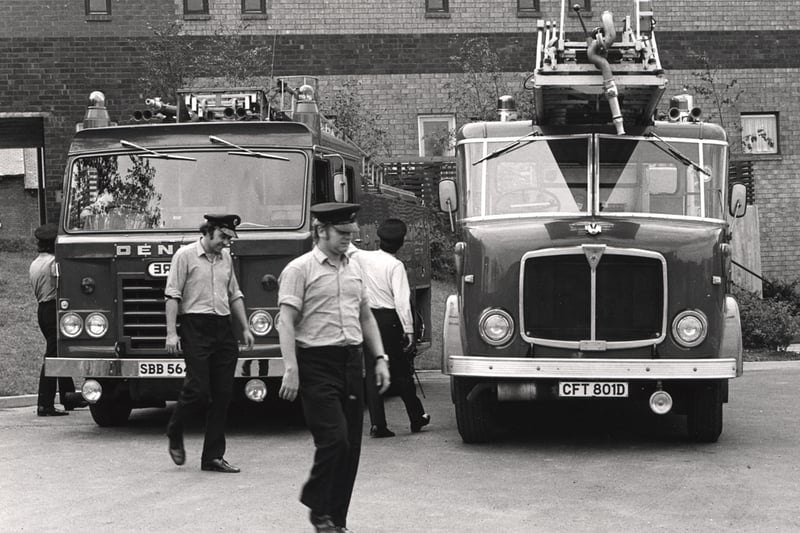 A view of firemen Newcastle upon Tyne taken in 1975. The photograph shows two fire engines which are parked in front of the Byker Wall. 