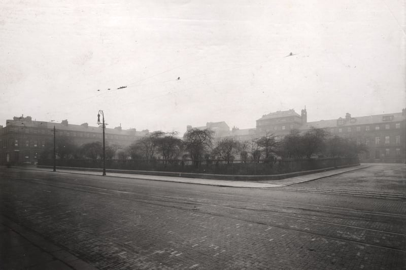  A view of Eldon Square Newcastle upon Tyne taken in 1914. The photograph has been taken from Blackett Street looking north-west. Two sides of Eldon Square can be seen. The central garden is surrounded by railings. Tramlines and tramwires can be seen in the foreground. 