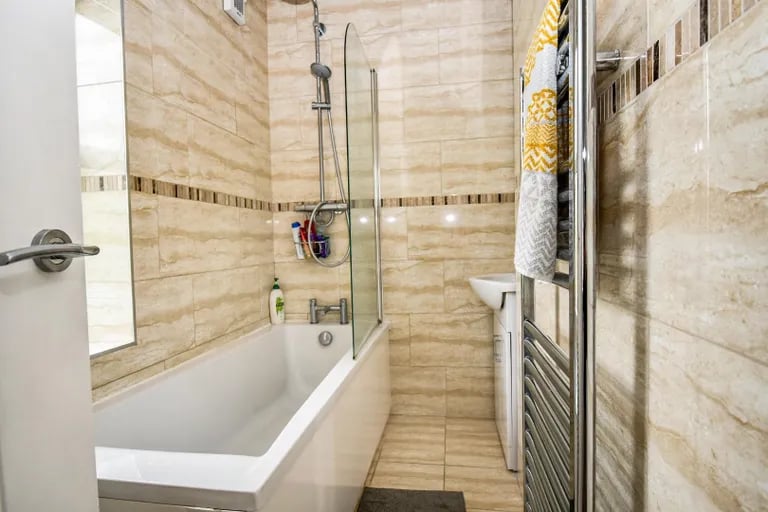 The house bathroom has a bathtub with chrome rain shower over.