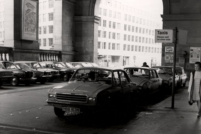 A view of the taxi rank underneath the main portico at the front of the station in 1975.