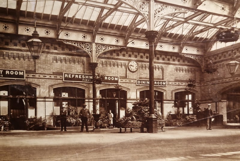 Fleetwood Railway Station in 1890. The emotive caption on the back says 'It's 9.45am and it almost smells like it. The air is warm, floral decoration has a summer lushness and the lad is sweeping the dust from the recreation room door in readiness for the morning customers.'