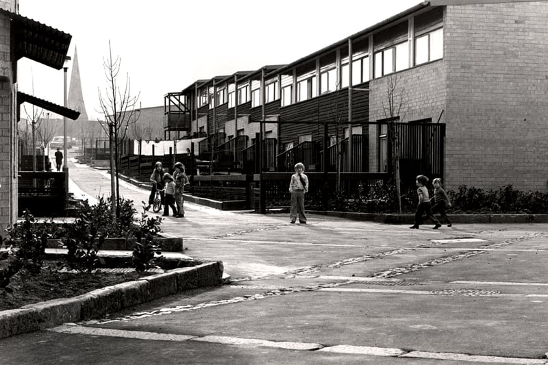  A view of Spires Lane Byker taken in 1976. The photograph shows modern housing with children playing outside. The spire of St. Michael's Church can be seen in the background. 