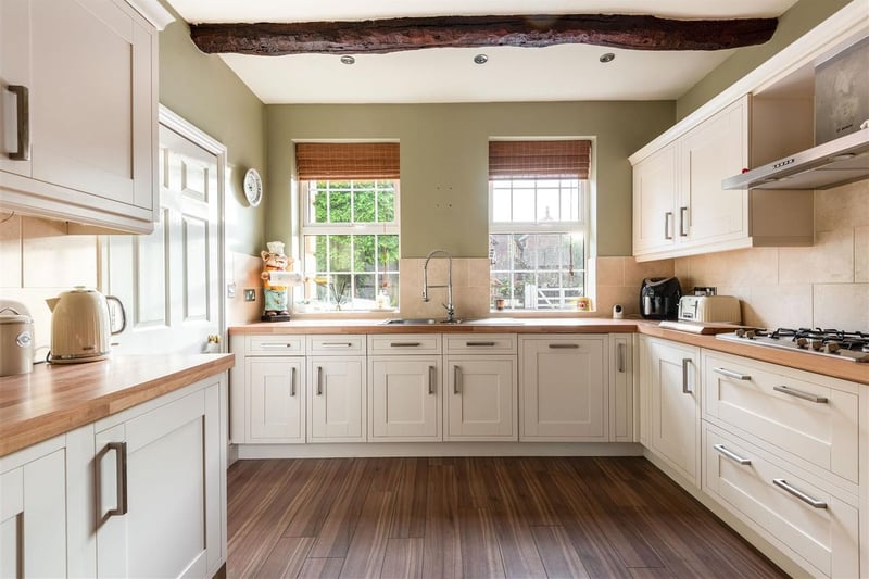 The kitchen includes an exposed wooden beam and integrated furniture and storage.