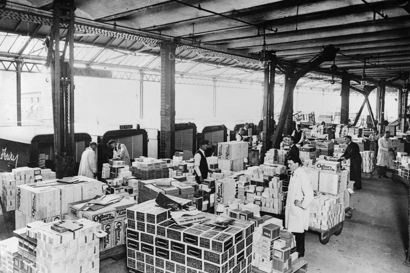 Dispatch depot at Cadbury's factory, Bournville, West Midlands, 1928. Boxes of Cadbury's chocolate and cocoa wait to be loaded into vans for delivery. Men in overalls prepare the goods for dispatch. In 1879 Cadbury's moved their business out to Bournville, then a rural site south west of Birmingham, where they established a new factory and model village.