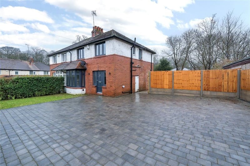 To the front is a small lawned garden and a driveway with ample parking for multiple vehicles.