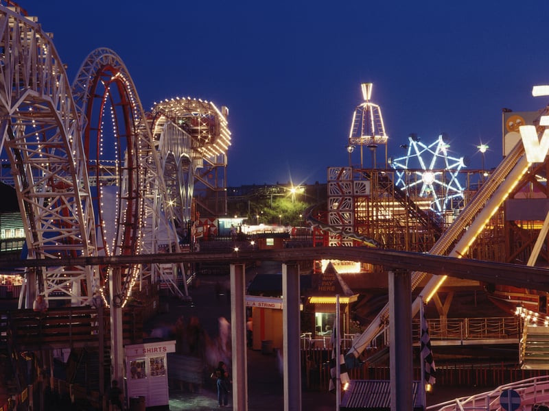 A night view of the illuminated rollercoaster and fun rides, 1983
