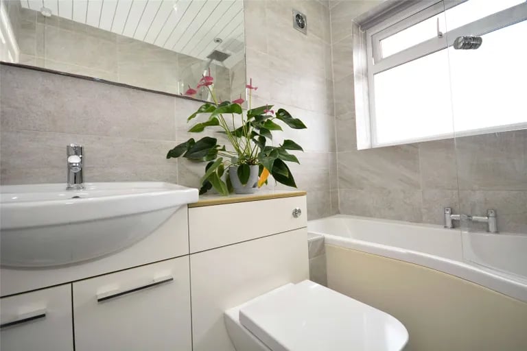 The fully tiled house bathroom provides relaxation with a bathtub with shower over.