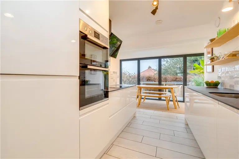 The open plan kitchen features white high gloss units and a range of built-in appliances.