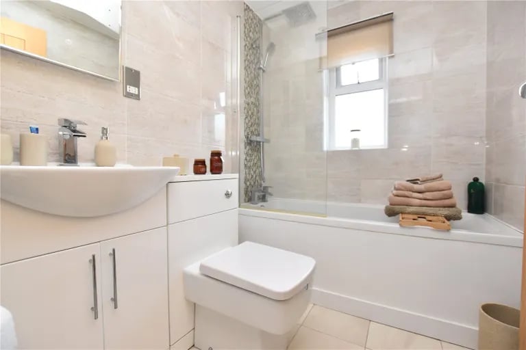 The fully-tiled house bathroom has a three piece suite with shower over the bath.