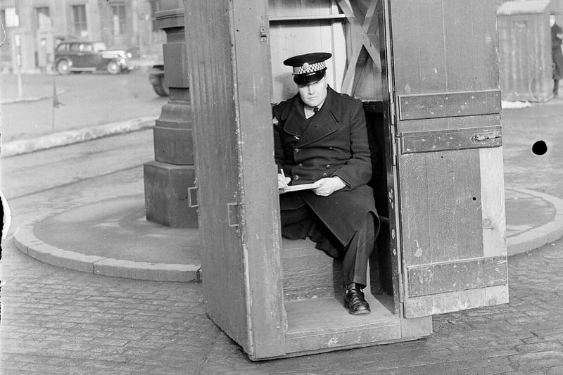 A policeman sitting in a night watchman's hut takes notes on traffic at Haymarket to monitor any bottle necks.