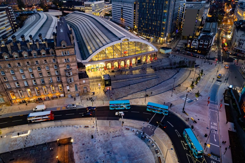 Buses travel past the train station at night and lights illuminate the pubs and bars on Lime Street to the right.