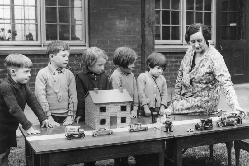 18th March 1936:  A 'Safety First' lesson in progress at Layton Junior School, Blackpool, Lancashire. A group of youngsters watch a teacher move toy cars on a model street.  (Photo by Fox Photos/Getty Images)