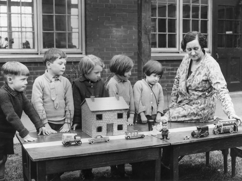 18th March 1936: A 'Safety First' lesson in progress at Layton Junior School, Blackpool, Lancashire. A group of youngsters watch a teacher move toy cars on a model street. (Photo by Fox Photos/Getty Images)