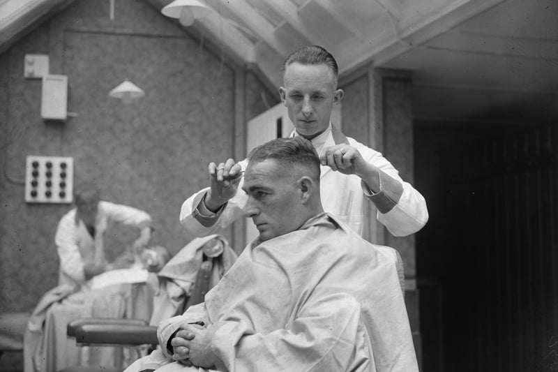 18th September 1933:  New Zealand batsman, 'Stewie' Dempster' (1903 - 1974) checking a client's haircut in a barber's shop which he hadopened in Blackpool.  (Photo by Fred Morley/Fox Photos/Getty Images)