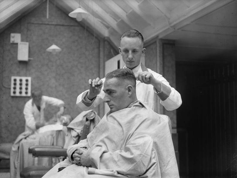 18th September 1933: New Zealand batsman, 'Stewie' Dempster' (1903 - 1974) checking a client's haircut in a barber's shop which he hadopened in Blackpool. (Photo by Fred Morley/Fox Photos/Getty Images)