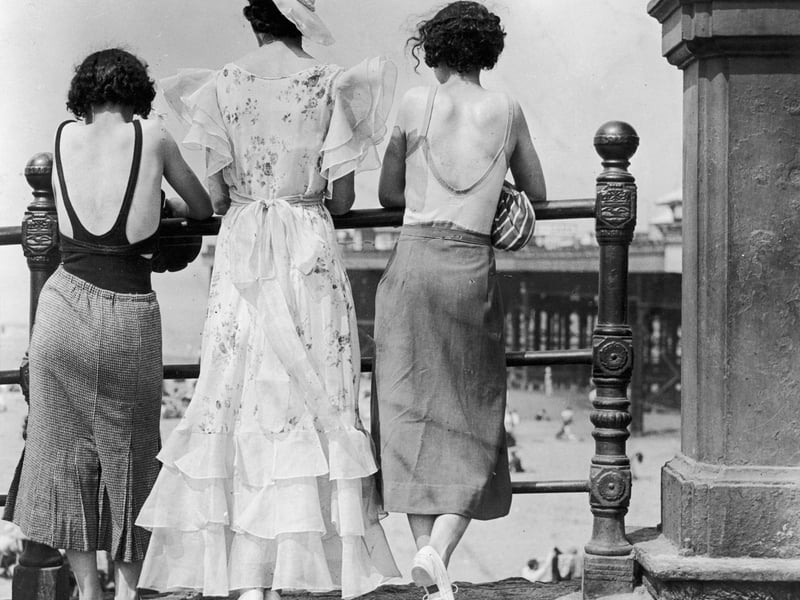 Three women on Blackpool promenade during a heatwave. One wears a divided skirt and the other a straight skirt, both over swimwear. The middle one has a 'copy' of the Letty Lynton dress made popular by Joan Crawford in the film of that name. Adapted for the mass market the triple row of frills at the hem are matched by frills at the shoulder forming cap sleeves.   (Photo by E  Dean/Getty Images)