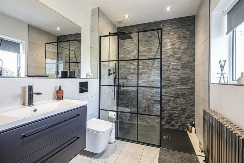 The ensuite is stylish, monochrome and well-lit with natural light thanks to large windows and the opposing mirror.