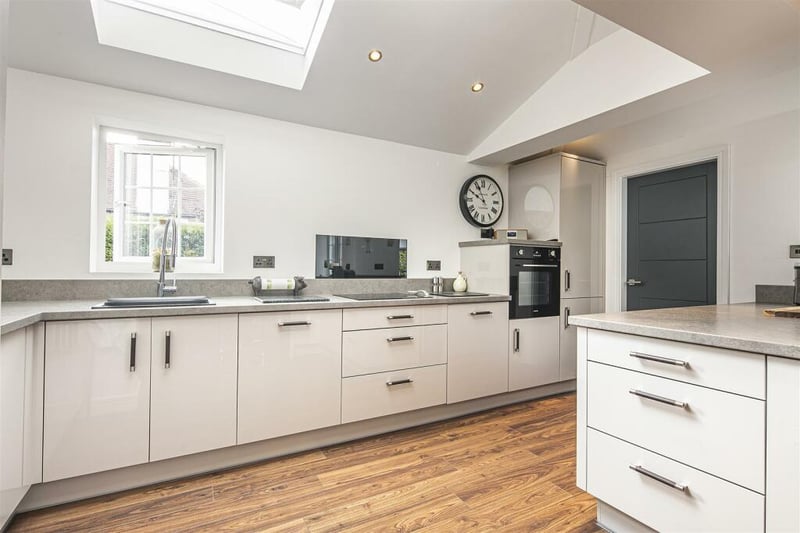 Integrated appliances include an electric oven, induction hob, a dishwasher, drinks chiller, and a fridge freezer. The door in the kitchen leads through to the utility room, WC and cloakroom.
