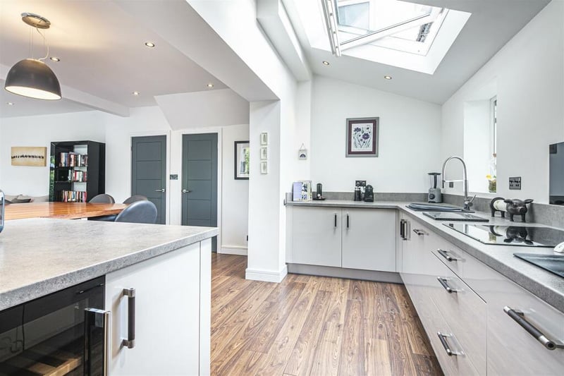 The kitchen area has a range of grey, high gloss fitted units with extensive worktop space.