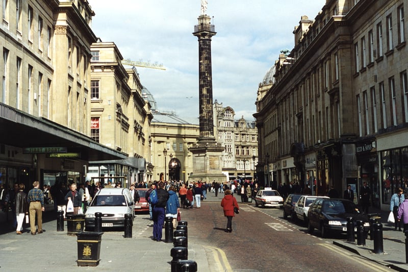 A view of Grainger Street Newcastle upon Tyne taken in 1995. The view is looking along Grainger Street towards Grey's Monument. It is a busy street scene. In the centre to the right is the entrance to the Central Arcade and to the left Nelson Street. Grey's Monument is in the background with Monument Mall behind. 