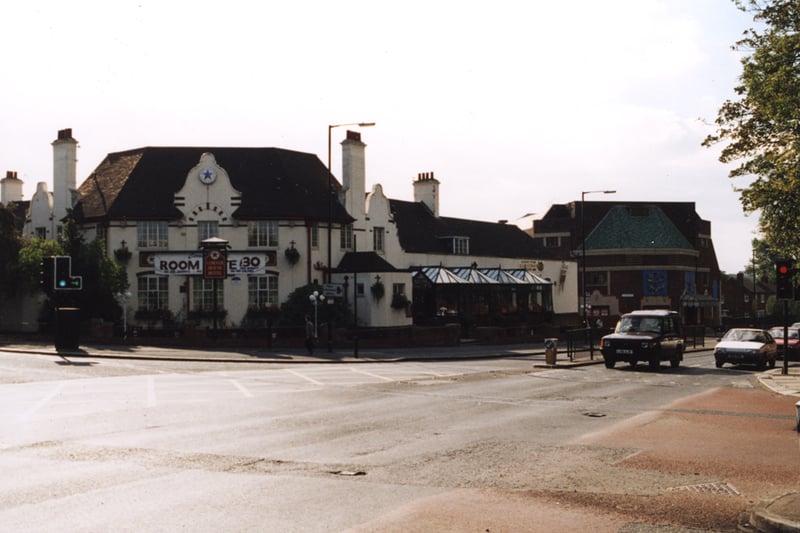 A 1995 photograph of the Corner House Hotel viewed from across Stephenson Road. The central section and right wing of the building can be seen. The People's Theatre is visible further down Stephenson Road. Cars are waiting at the traffic lights in the left hand lane of Stephenson Road.