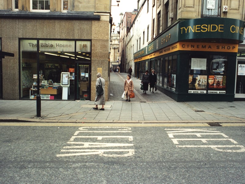 A view of High Friars Lane/Pilgrim Street Newcastle upon Tyne taken in 1995. The photograph has been taken from one side of Pilgrim Street looking across to the other side. 'The Bible House' is in the centre to the left. High Friars Lane which runs to Grey Street is to the right of 'The Bible House'. The Central Exchange Buildings can be seen at the end of High Friars Lane. The Tyneside Cinema is at the junction of Pilgrim Street and High Friars Lane. 