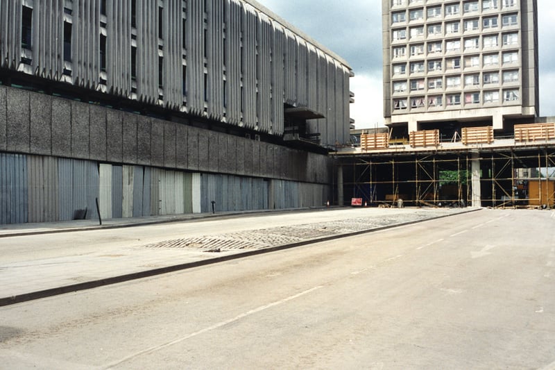  A view of John Dobson Street Newcastle upon Tyne taken in 1995. The photograph shows John Dobson Street after part of the decking which crosses the road has been removed. The City Library is to the left with the ground floor windows covered in sheets of corrugated iron. Bewick Court is in the background standing on the remaining piece of decking.