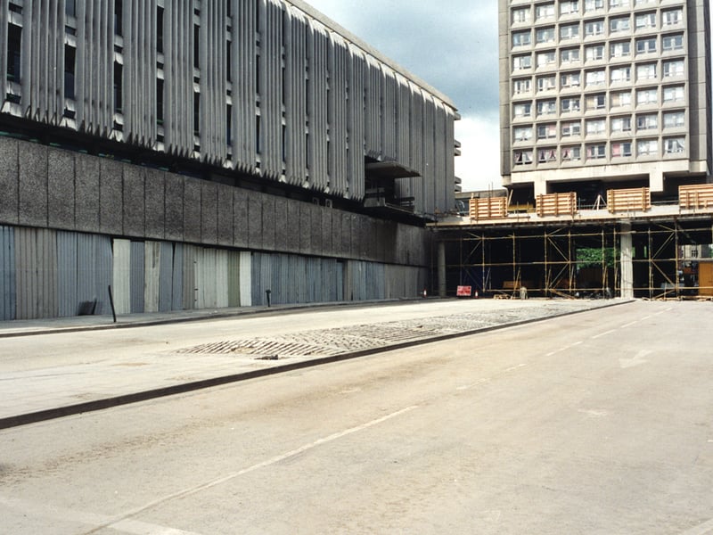  A view of John Dobson Street Newcastle upon Tyne taken in 1995. The photograph shows John Dobson Street after part of the decking which crosses the road has been removed. The City Library is to the left with the ground floor windows covered in sheets of corrugated iron. Bewick Court is in the background standing on the remaining piece of decking.