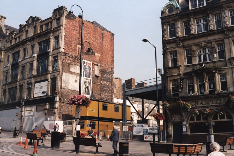 A 1998 photograph of part of the Bigg Market. The photograph has been taken from the middle of the road looking across to the Chambers public house and the building work which is taking place on the site of the former Binns department store. 