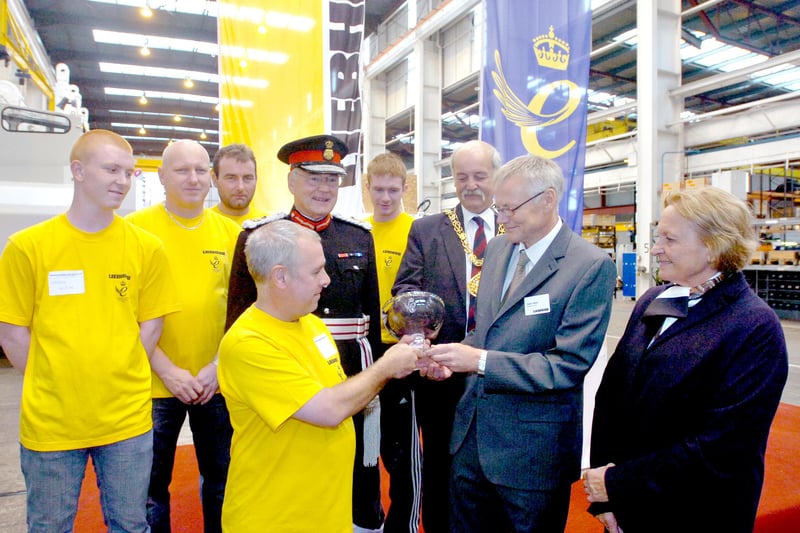 The workers take a first look at the Queen's Award which was bestowed on the company 15 years ago.