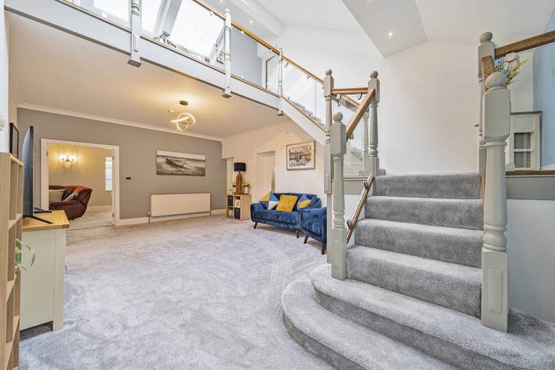 A large reception hall with skylight windows and grand stairs sits to the rear of the property.