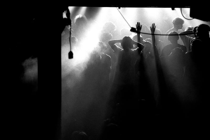 A clubber raises their hands on an atmospheric main stage during a break in the music at the Hacienda, Manchester 1988. 