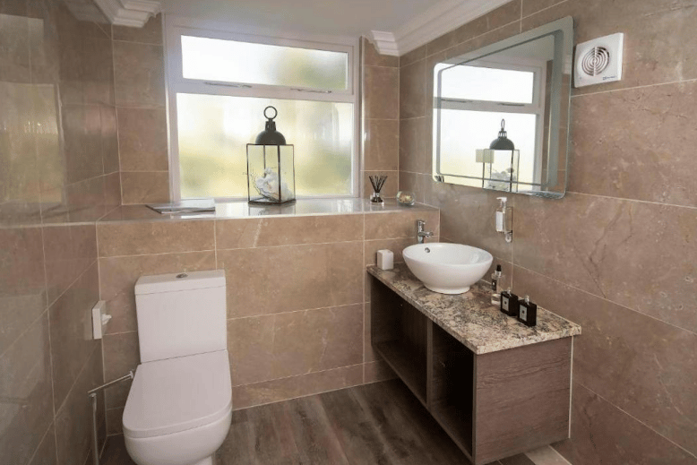 The bathroom has contemporary furniture and tiling and a floating cupboard