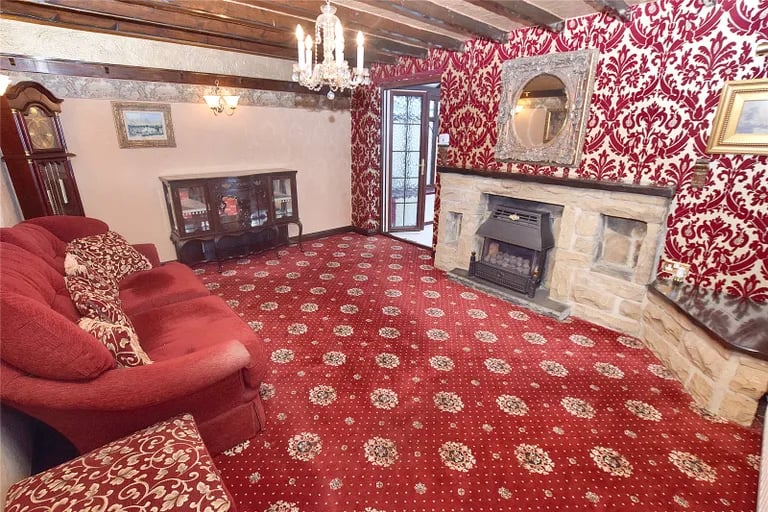 On the other side of the hall is this living room with stone fireplace and has fire, a bow window to the front elevation and double doors to the conservatory.