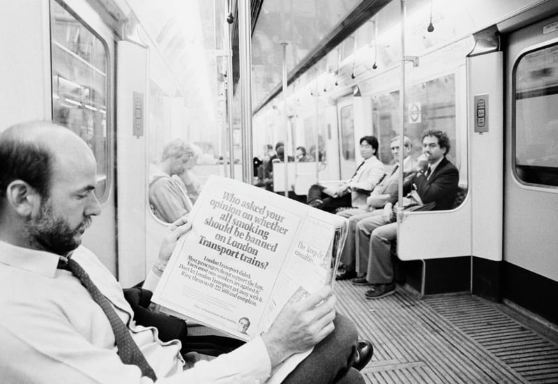 A man reads a newspaper while travelling on a London Underground train on the day following the ban on smoking, London, UK, 10th July 1984. (Photo by Len Trievnor/Daily Express/Hulton Archive/Getty Images)