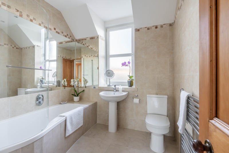 The fully-tiled bathroom suite with an over-bath shower, heated towel rail and downlights.