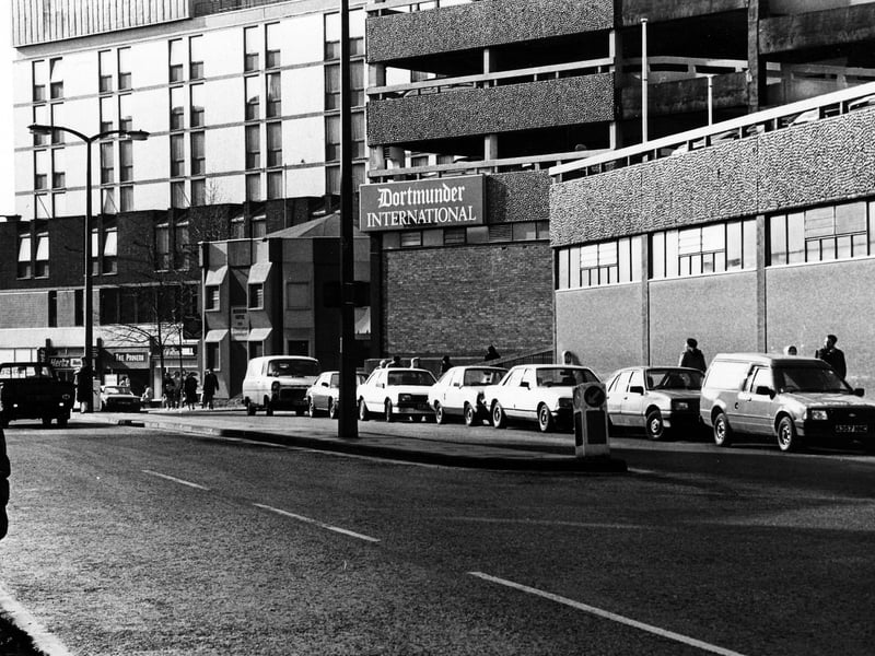 the Merrion Centre from Wade Lane, with Dortmunder International public house in the centre. To the left of this is the Merrion Hotel, then William Hill bookmakers, The Proverb restaurant and Hertz car rentals. Pictured in February 1985.